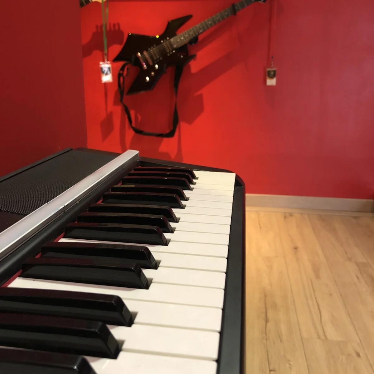 Le clavier et une guitare électrique sur le mur rouge du Studio