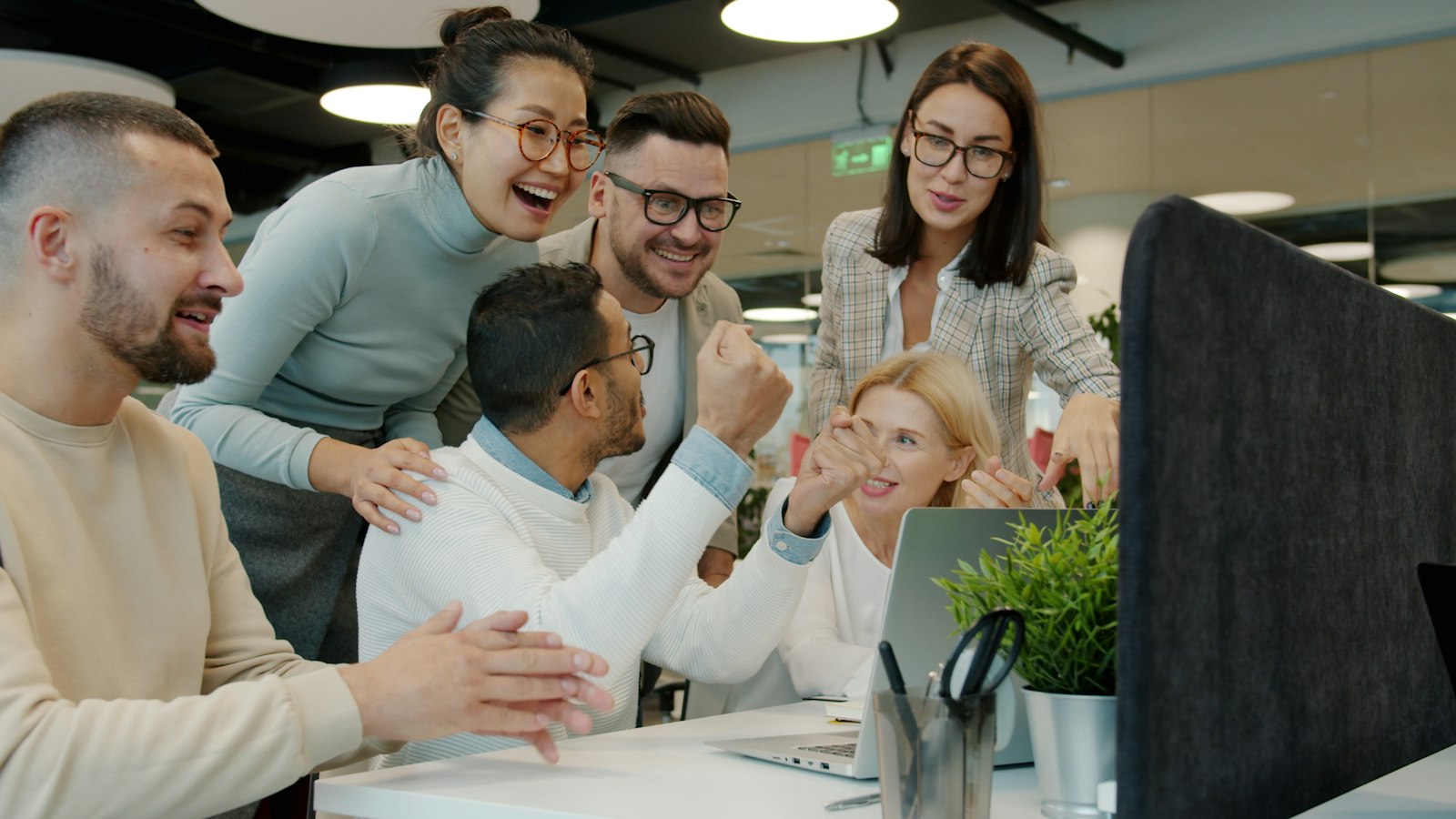 Une équipe de collègues célèbre une victoire autour d’un bureau